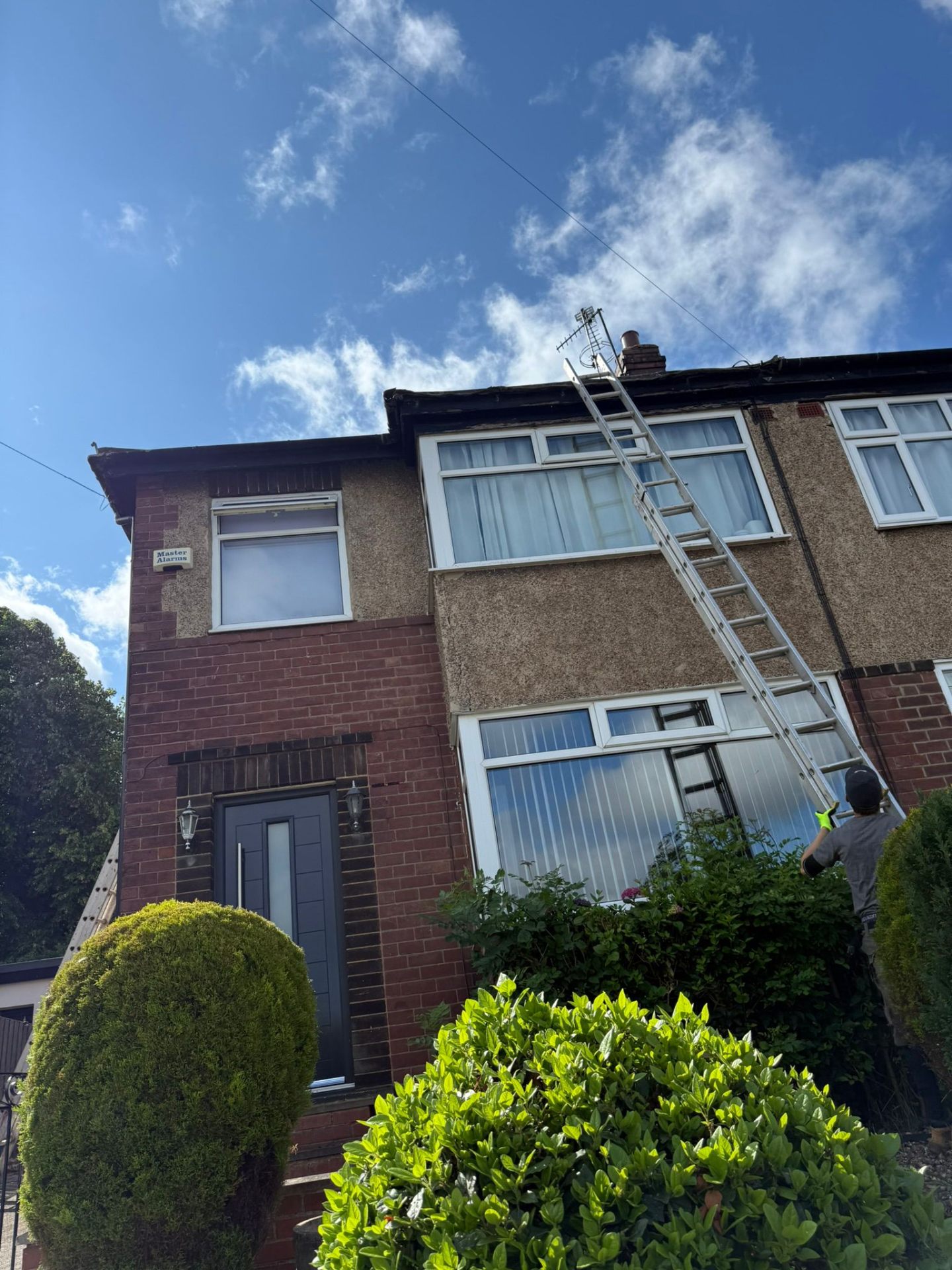 Roofer on ladder inspecting a semi-detached roof in Leeds